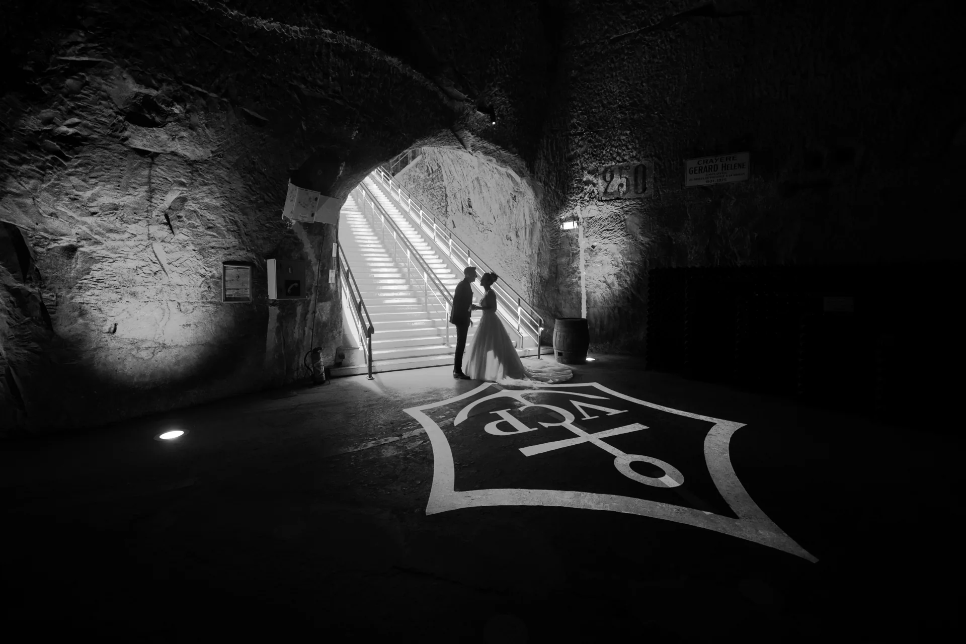 Les silhouettes des mariés face à face dans la lumière d’une crayère.