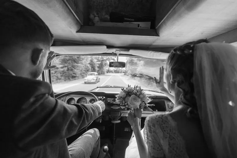 Les mariés dans une voiture ancienne.